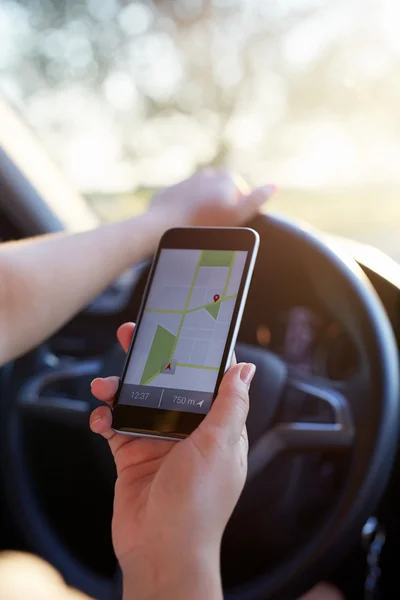 Woman in the car holding black mobile phone with gps map — Stock Photo, Image