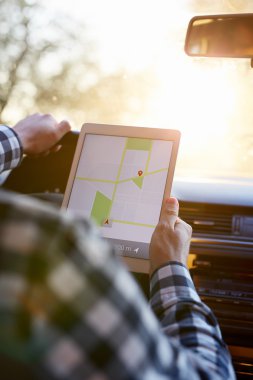 Arabada oturan ve tabletnavigation tutan adam