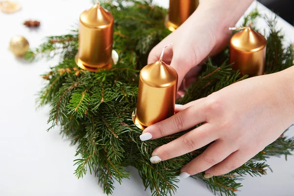 Mujer fija vela en una corona de Navidad — Foto de Stock