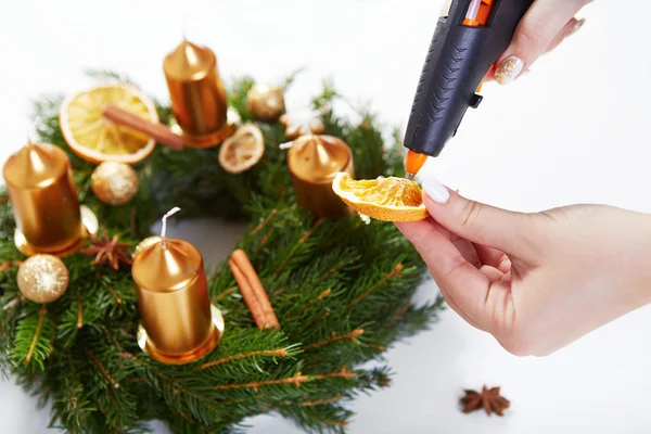 Mujer pegando pistola de fusión naranja en la corona de Navidad — Foto de Stock