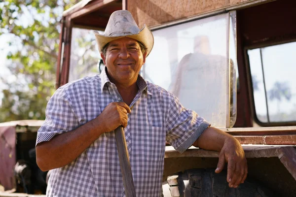 Retrato hombre feliz granjero apoyado en tractor mirando a la cámara —  Fotos de Stock