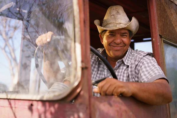 Retrato feliz homem agricultor condução trator olhando para a câmera — Fotografia de Stock