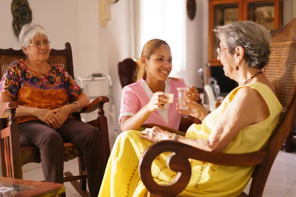 Hospice verpleegkundige portie pil geneeskunde Water naar de oude vrouw — Stockfoto