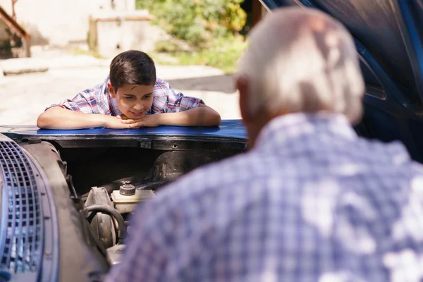Ragazzo con nonno apprendimento auto motori da anziano uomo — Foto Stock