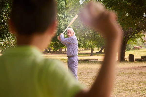Дідусь і онук Хлопчик грає в бейсбол в парку Ліцензійні Стокові Зображення