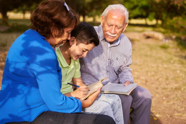 Grand-père et grand-mère aider petit-fils avec les devoirs — Photo