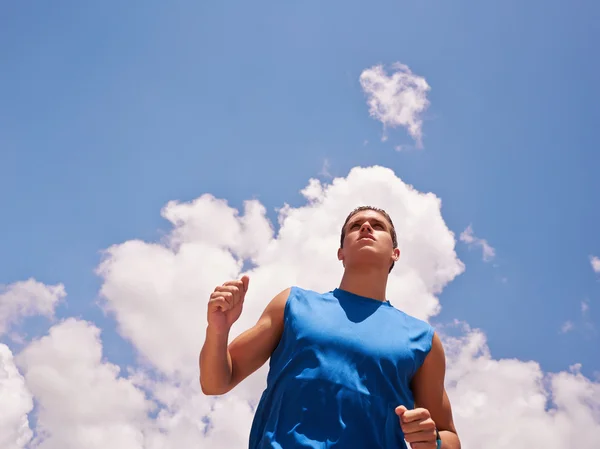 Νεαρός άνδρας κάνει σπορ δρομέα τζόγκινγκ μπλε ουρανό — Φωτογραφία Αρχείου