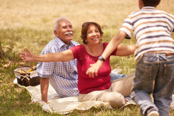 Abuelos Senior pareja abrazando joven chico en picnic — Foto de Stock