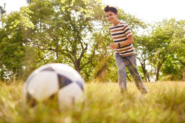 Genç oğlan topa vuruyor futbol oyunu oynarken