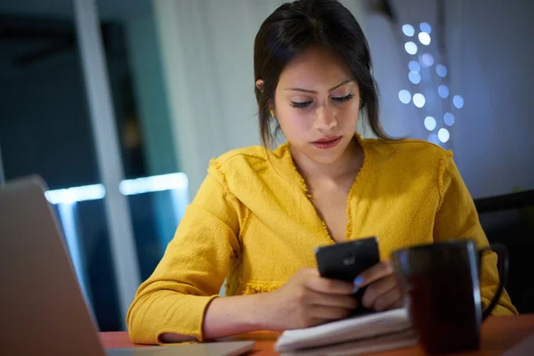 Collegestudent som studerar på natt typer meddelande på telefon — Stockfoto