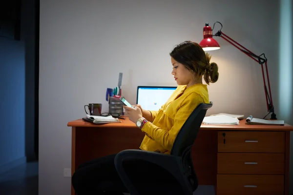 Chica estudiante estudiando en la noche tipos mensaje en el teléfono —  Fotos de Stock