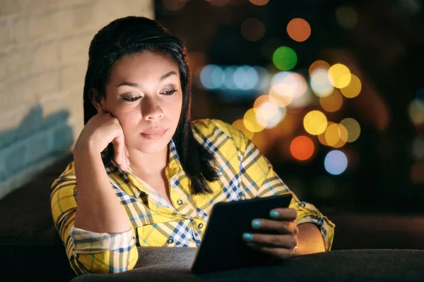 Jonge vrouw houdt lezer en het lezen van het boek 's nachts — Stockfoto