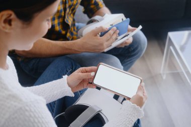 Genç çift koltukta kulaklıkla sanal gerçeklik oynuyorlar.