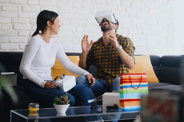 Junges Paar spielt Virtual Reality mit Headset auf Sofa Stockfoto