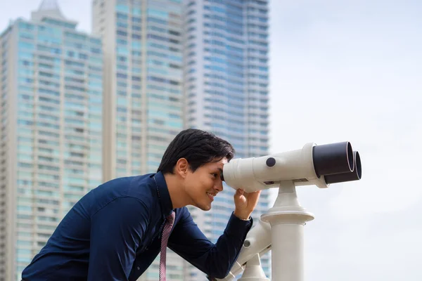 Hombre de negocios asiático con prismáticos mirando a la ciudad —  Fotos de Stock