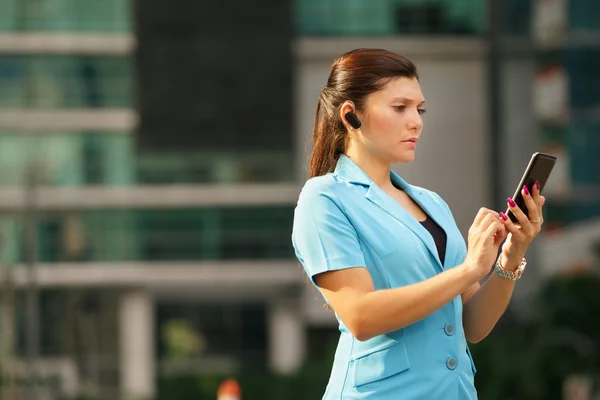 Biznes kobieta podejmowania telefon z urządzeniem bluetooth — Zdjęcie stockowe