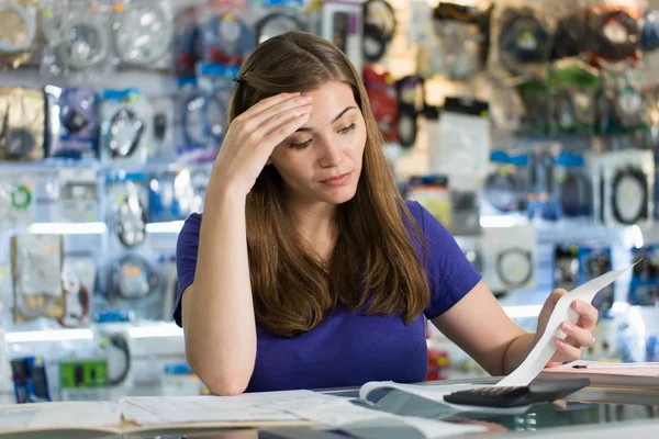 Besorgte Frau prüft Rechnungen und Rechnungen im Computerladen — Stockfoto