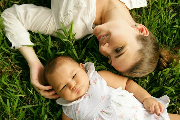 Mère avec Caresser bébé fille pose sur l'herbe — Photo