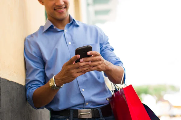 African American Man schrijven bericht op telefoon Shopping tassen — Stockfoto