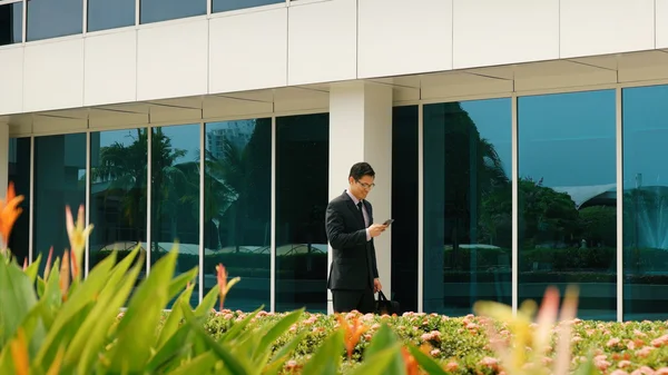 Uomo d'affari che chiacchiera sul telefono cellulare a piedi in ufficio — Foto Stock