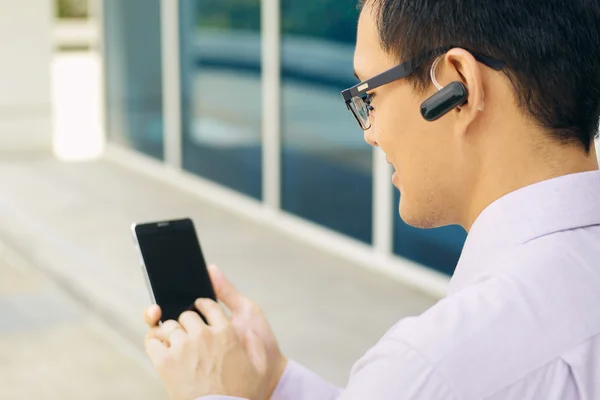 Empresário chamando no telefone móvel com fone de ouvido Bluetooth — Fotografia de Stock