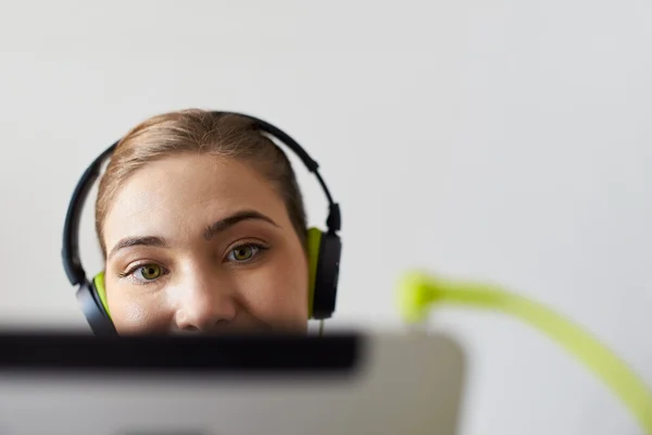 Frau mit grünen Kopfhörern hört Podcast-Musik auf Tablet-PC — Stockfoto
