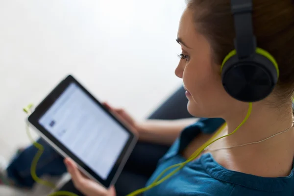 Mulher com fones de ouvido verdes ouve música Podcast no Tablet PC — Fotografia de Stock