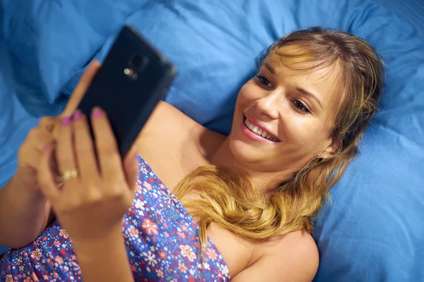 Menina na cama leitura amor telefone mensagem do namorado — Fotografia de Stock