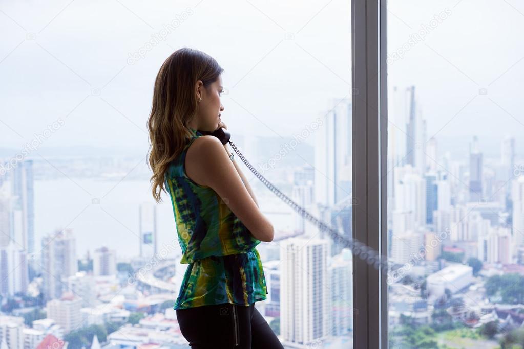 Woman Talking With Wired Telephone In Office Looking Outside Win