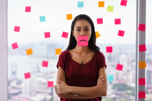 Beschäftigte Person hält klebrigen Zettel mit Emoticon am Mund — Stockfoto