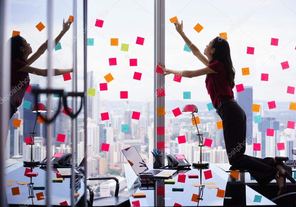 Busy Person Attaching Many Sticky Notes On Large Window
