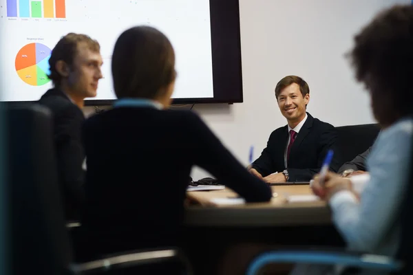 Uomini d'affari in ufficio sala riunioni con grafici in TV — Foto Stock