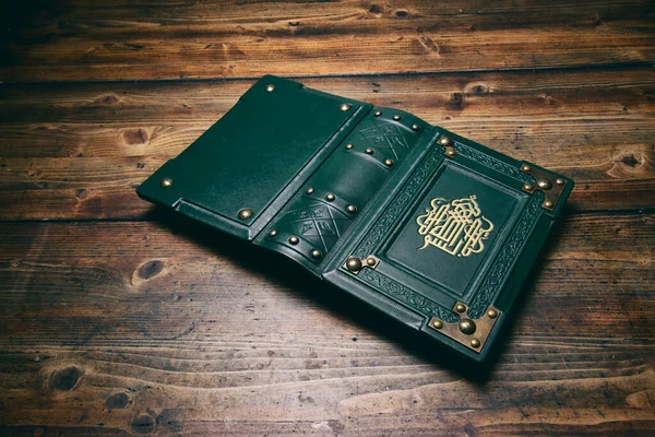 Ön kapağında yaldızlı el yazısı olan yeşil deri kitap masaya uzanırken ele geçirildi. İngilizce çevirisi: 