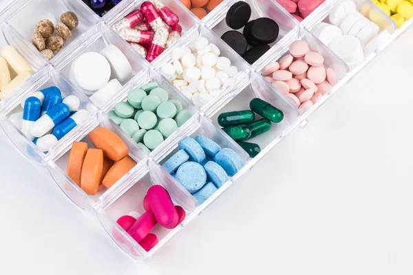 Různé tabletky a kapsle v nádobě z plastu — Stock fotografie