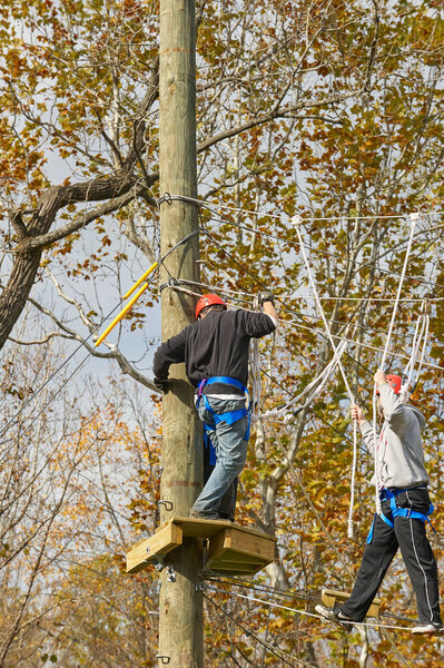 High ropes / challenge course. Участник на верхней платформе и участник, идущий по канатам