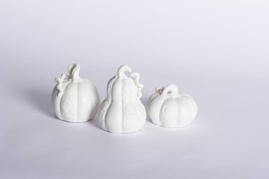  Three white ceramic pumpkins on white paper background. Photo studio shot