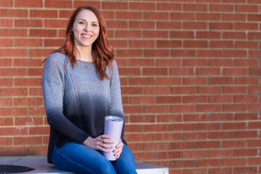 Muhteşem sarışın bir model, en sevdiği içeceği içerken dışarıda bir bahar gününün tadını çıkarıyor.