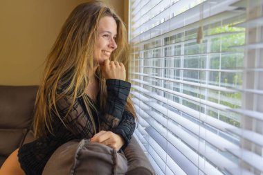 Muhteşem bir esmer model iç çamaşırlarıyla ev ortamında poz veriyor.