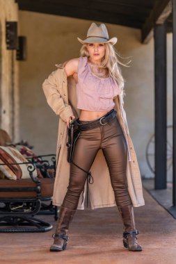 Kovboy gibi giyinmiş muhteşem sarışın bir manken. Açık havanın tadını çıkarıyor.