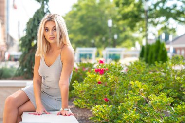 Sarışın bir model yaz gününün tadını çıkarırken dışarıda poz veriyor.