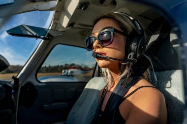 Sarışın bir model, yerel bir havaalanında tek motorlu bir uçakla dışarıda poz veriyor.