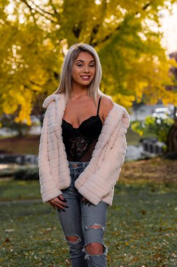 Genç ve güzel bir sarışın model, bir sonbahar gününün tadını çıkarırken dışarıda poz veriyor.