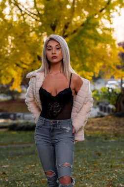 Genç ve güzel bir sarışın model, bir sonbahar gününün tadını çıkarırken dışarıda poz veriyor.