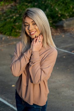 Genç ve güzel bir sarışın model, bir sonbahar gününün tadını çıkarırken dışarıda poz veriyor.