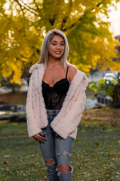 Genç ve güzel bir sarışın model, bir sonbahar gününün tadını çıkarırken dışarıda poz veriyor.