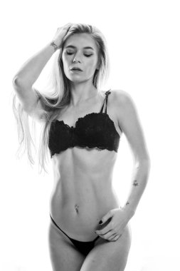 Çekici sarışın bir iç çamaşırı modeli stüdyo ortamında poz veriyor.