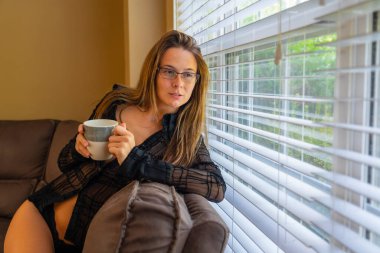 Muhteşem bir esmer model iç çamaşırlarıyla ev ortamında poz veriyor.