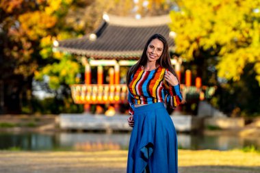 Muhteşem bir esmer model, sonbahar havasının tadını çıkarırken dışarıda poz veriyor.