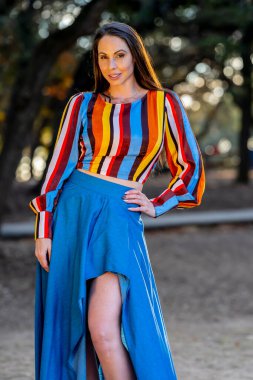 Muhteşem bir esmer model, sonbahar havasının tadını çıkarırken dışarıda poz veriyor.