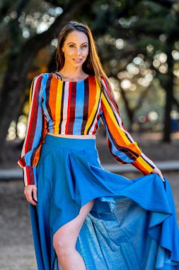 Muhteşem bir esmer model, sonbahar havasının tadını çıkarırken dışarıda poz veriyor.